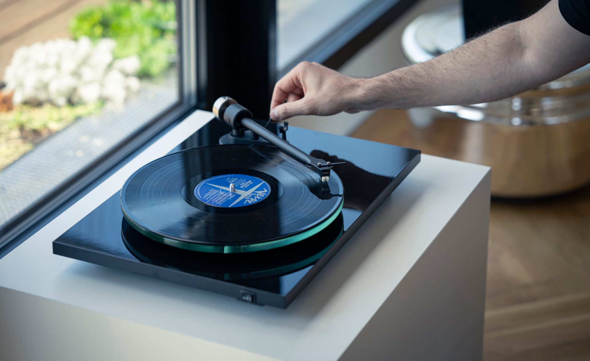 T2 W playing a record on a white box in front of a window